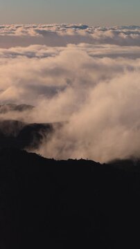 Vertical 4K hikers walking on a mountain ridge above the clouds at sunrise, Pico do Arieiro, Madeira