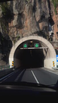Driving on the VR1 highway toward tunnels carved into volcanic rock, Funchal region
