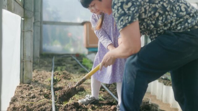 Grandmother and Child Gardening Together in a Greenhouse
