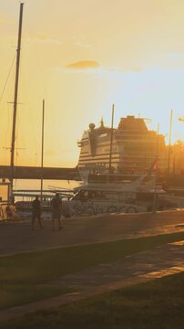 Vertical 4K silhouette of travelers walking along Funchal marina at sunset