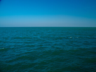 Obraz premium Serene tropical beach with crystal clear turquoise water, gentle waves, and a bright blue sky with fluffy white clouds. peaceful and relaxing summer scene perfect for panorama and travel concepts.