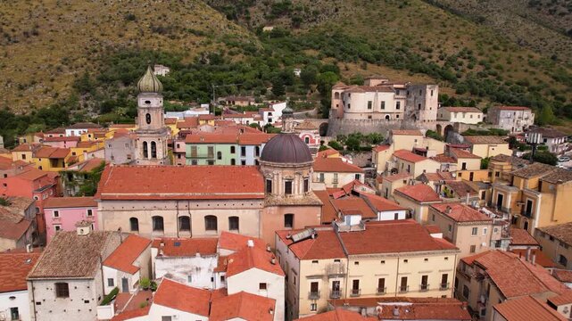 Venafro aerial 4k view flying over church domes to Castello Pandone in Italy. Cinematic drone low flight over rooftops to medieval castle in Molise. Historic cathedral and fortress scenery