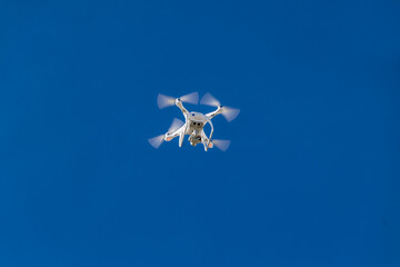Small commercial drone isolated in an open blue sky