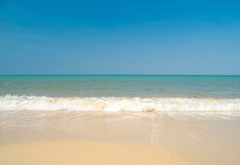 Fototapeta premium Peaceful panorama tropical sea beach with gentle waves rolling onto golden sand under bright blue sky with fluffy white clouds. relaxing summer scene perfect scene for travel holliday and nature lover