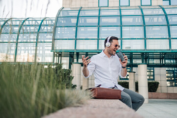 Fototapeta premium Businessman listening to music and singing with smartphone