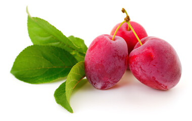 Obraz premium Three red plums with green leaves isolated on white background