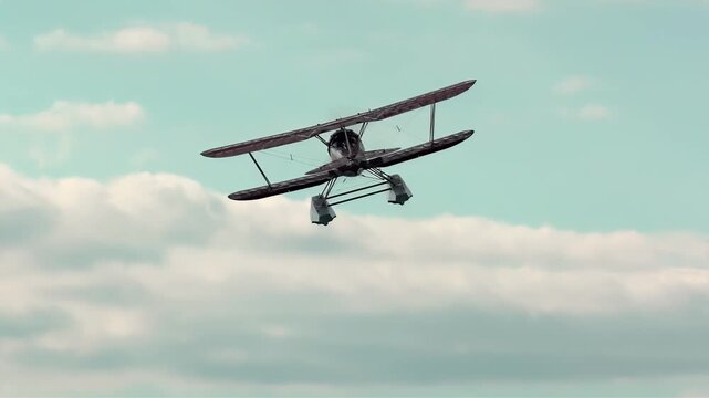 Vintage seaplane soaring through a cloudy sky on a bright day