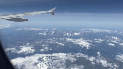 Obraz premium Spectacular aerial view from an airplane window flying over the snow-capped Alps mountain range