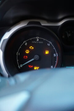 Close-up of a car dashboard with multiple warning lights illuminated, including check engine, battery, and oil pressure icons, signifying mechanical trouble.