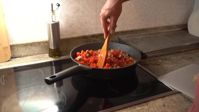 Male cook preparing a classic italian tomato and meat sauce for pasta on an induction cooktop