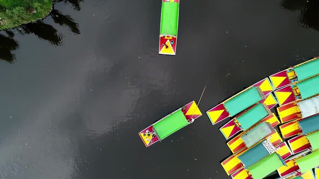 Aerial view of colorful trajineras boats gathered on a dark canal, a vibrant scene