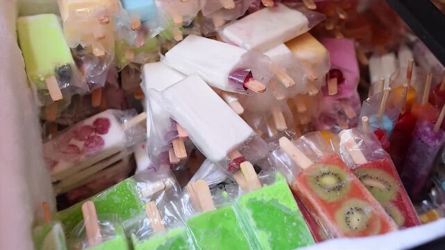 Assortment of colorful frozen fruit popsicles and ice cream bars in plastic wrappers