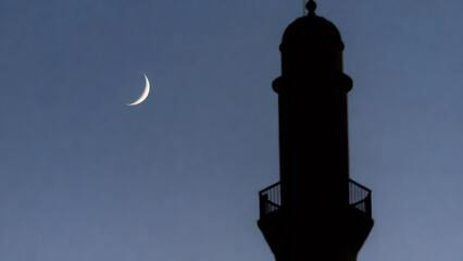 Obraz premium Crescent moon in blue sky silhouetted by mosque minaret. Ramazan concept. Islamic religious holiday or spiritual devotion.