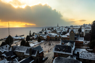 sunset and   snow in Bariloche's main square, with Alpine-inspired architecture and the cathedral tower in the background. San Carlos de Bariloche, Patagonia, Argentina. Andes Mountains