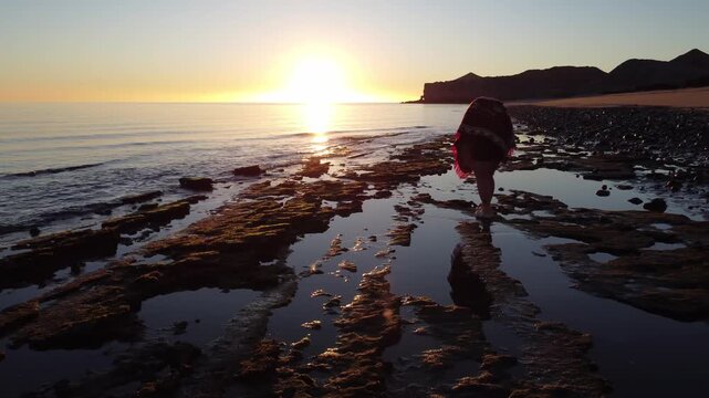 Woman on ocean coastline exploring tide pools