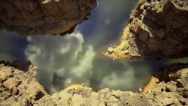 Overhead rocky inlet with green reflective water, abstract interplay of rock channels and tide lines, cloud reflections creating painterly textures, modern