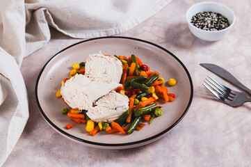 Chicken fillet and mexican mixed vegetables steamed on a plate on the table