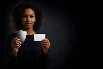 Naklejka premium Portrait of woman holding a shield symbol and blank card to illustrate cybersecurity, privacy protection and secure identity for business and startups