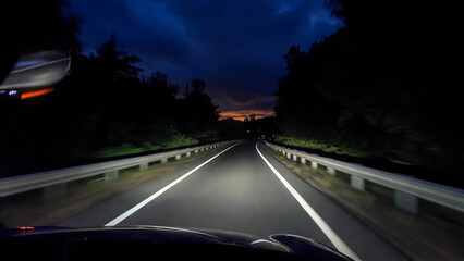 Obraz premium Driving on a dark highway at night with headlights illuminating the road.