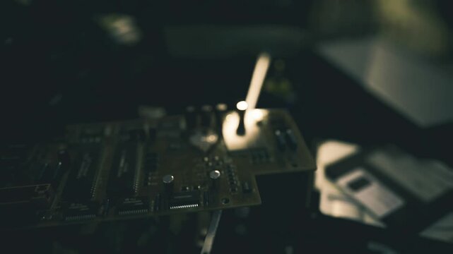 Forgotten floppy disk beside motherboard, salvage artist cataloguing parts, dust motes, warm vintage glow, neglected electronics, industrial nostalgia