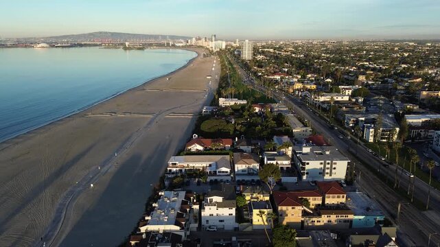 Coastal grid overview from Belmont Shore dense blocks frame East Ocean Blvd near Veterans Memorial Pier. Warm light over mixed roofing, soft beach textures, long palm shadows, Long Beach, CA