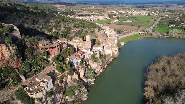 Tilt down aerial shot of Miravet town and Ebro river on sunny winter day. Tarragona, Spain.