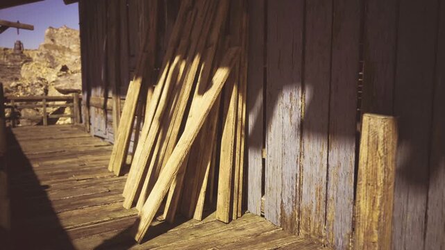 Sunlit Namibian shed stacked with planks, weathered boards leaning against blue corrugated siding, dusty sand floor, long warm shadows, textured timber grain