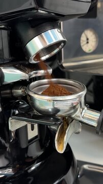 Espresso machine fills portafilter with ground coffee in a modern kitchen