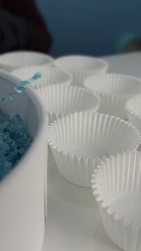 White cupcake liners arranged on table with blue decorative paper nearby