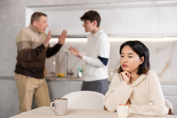 Obraz premium Young girl is tired of domestic quarrels. Relatives quarreling in the background