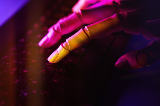Robotic hand typing on a colorful illuminated keyboard