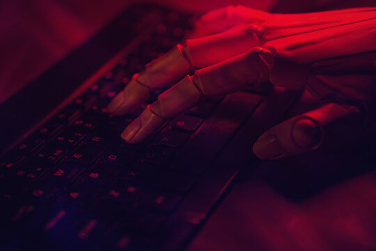 Robot hand typing on illuminated keyboard