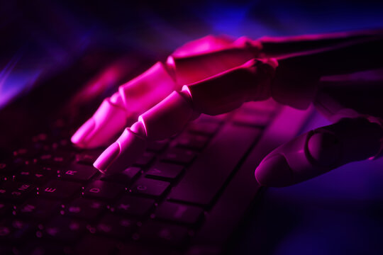Robotic hand typing on keyboard in dim purple light