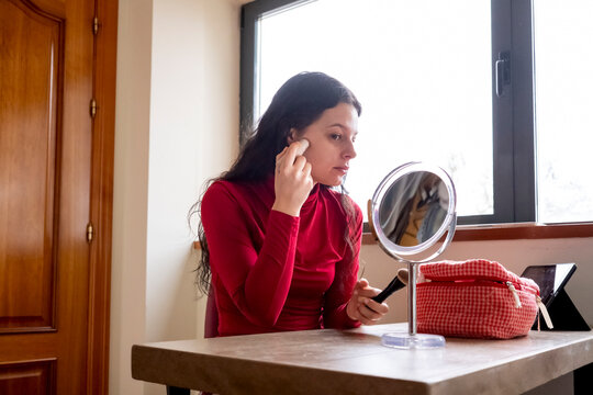 Woman applying makeup in front of a mirror