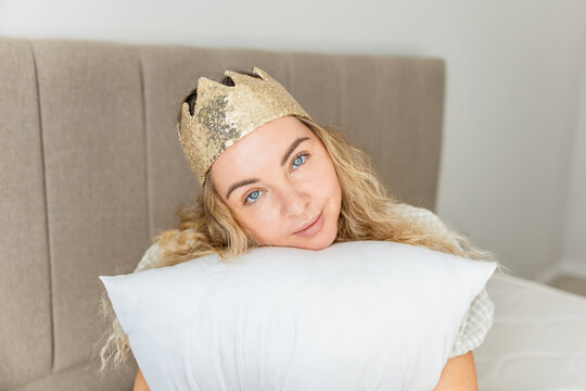Woman with a crown resting on a pillow at home