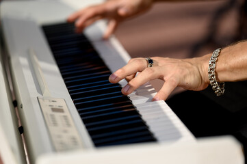 Fototapeta premium Hands playing piano keys on electronic keyboard in outdoor setting
