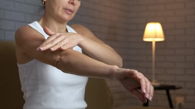Woman using a spiky ball for arm self massage. Middle-aged woman performing a self-massage on her arm with a small spiky ball to relieve muscle tension and pain