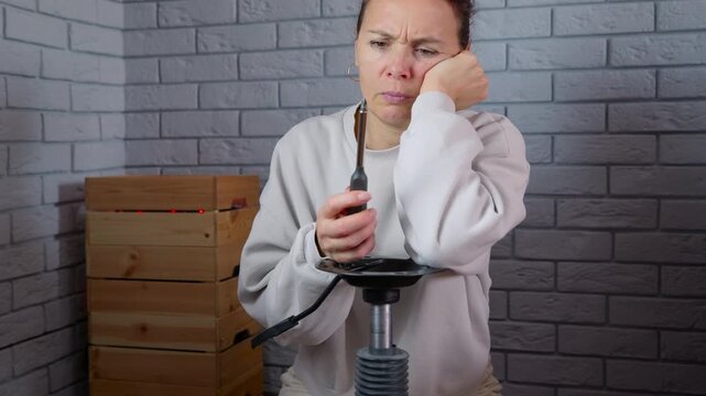 Frustrated woman failing to repair something with screwdriver. Puzzled middle-aged woman looking confused and disappointed while trying to fix with a screwdriver, showing her frustration