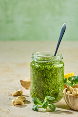 Fresh homemade green sprout pesto in glass jar on sunny kitchen table with ingredients