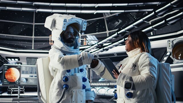 Cosmonaut doing fist bump with colleague, leaving starship to descend on planet during mankind survival expedition. Astronaut putting helmet on, exiting spaceship to colonize planet
