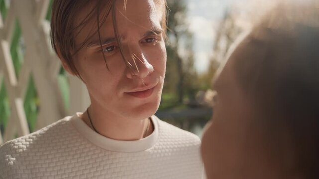 White man gazing at black woman lakeside with soft sunlight through autumn trees, closeup on thoughtful expression and subtle tear, calm voice and quiet promise of commitment, contemplative mood,