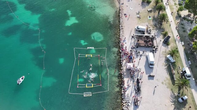 Summer water polo match in open sea near Omis, Dalmatia, Croatia with city beach in background.