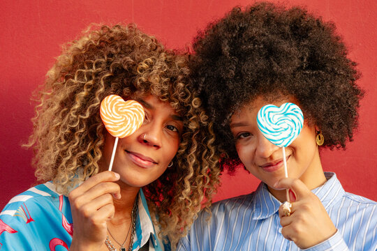 Two friends enjoying heart shaped lollipops downtown
