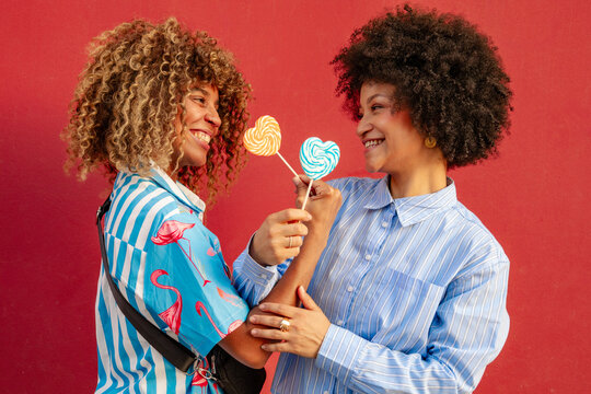 Two friends enjoying colorful lollipops downtown