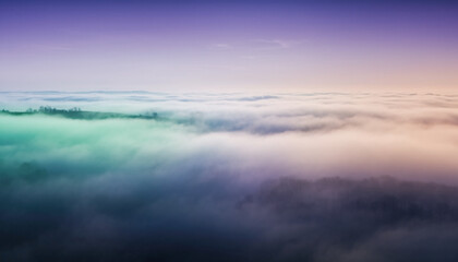 Obraz premium Aerial view of a cloudy landscape with a gradient purple and orange sky above the fog.