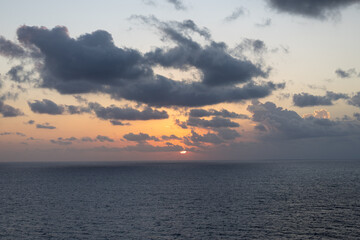 Obraz premium Soft Caribbean Sunrise with Orange Horizon and Scattered Clouds Over the Ocean