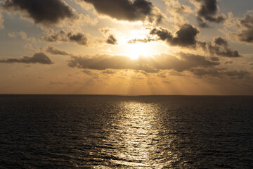 Obraz premium Golden Sunrise Over the Caribbean Sea with Dramatic Sun Rays and Ocean Reflection