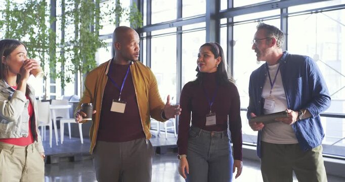 Prompted by question, diverse coworkers walking in office lounge, tapping tablet and shaking hands