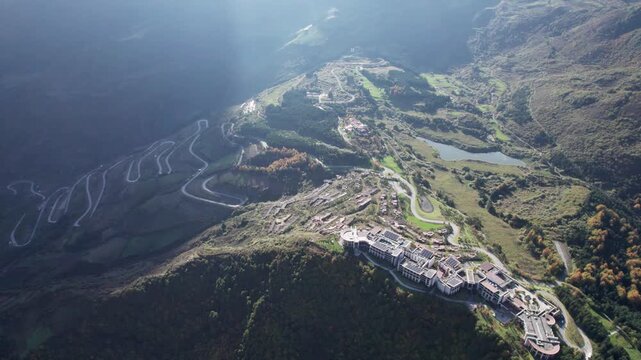 Drone view of abandoned resort buildings on the mountaintop near Jiuzaigou, Sichuan, China. Unfinished holiday village on top of mountain with zigzag road to it. 4k real time footage