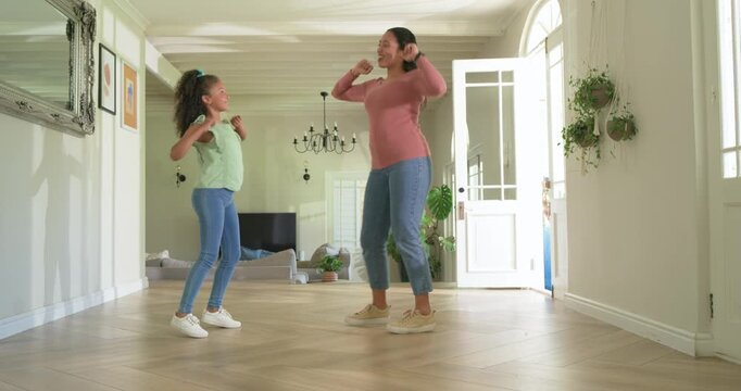 Mother and preteen daughter practicing dance, mother leading while daughter mirrors on wood floor